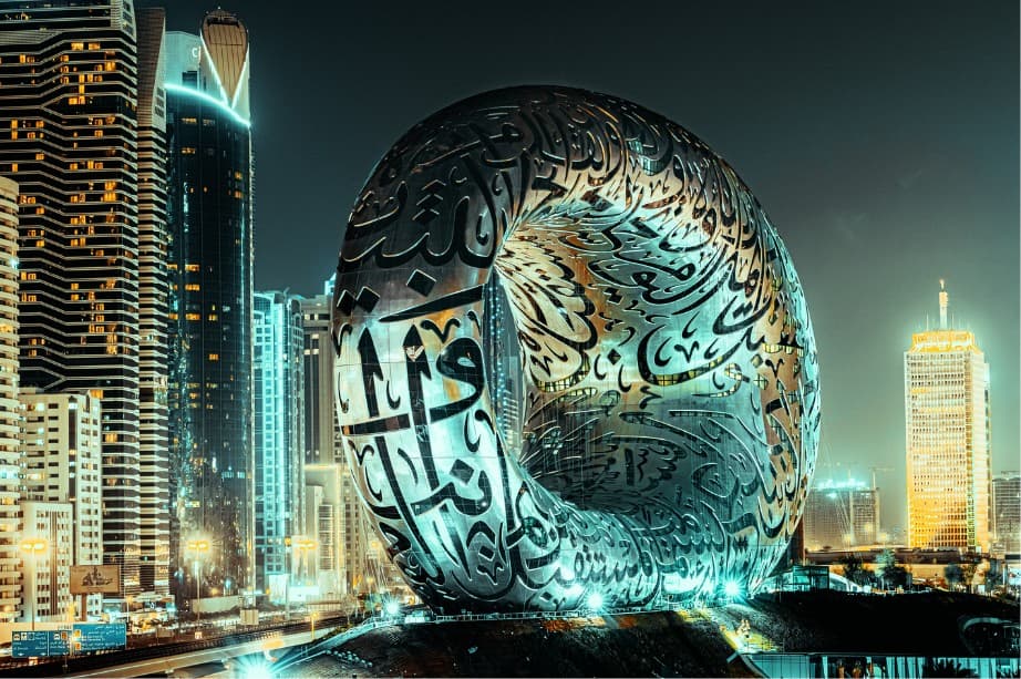 The Museum of the Future in Dubai lit up at night, its ring-shaped facade covered in Arabic calligraphy