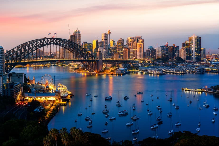 Sydney Harbour at dusk with the Harbour Bridge, the city skyline and yachts moored in Lavender Bay